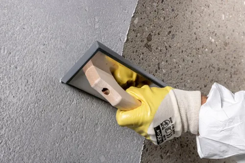 The fine filler Nafufill EF is applied as pore and cavity levelling mortar using a hard rubber grating board. <br>&copy; MC-Bauchemie 2026